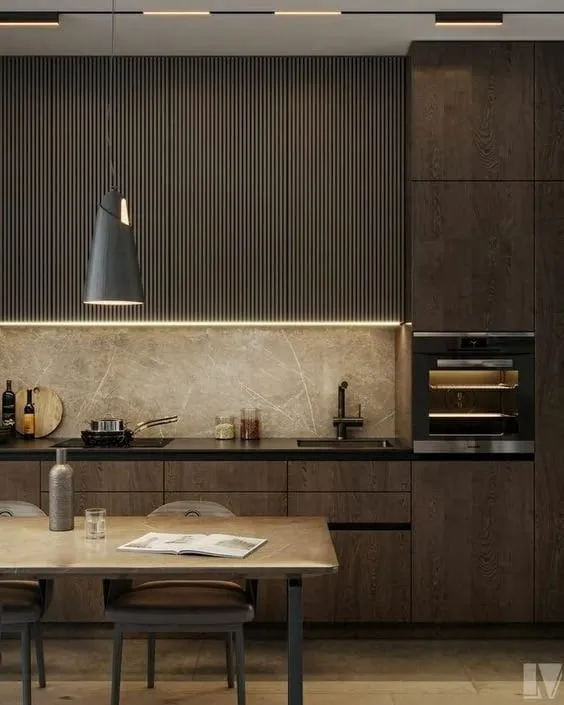 Single-wall kitchen with dark oak cabinets, a slatted wood wall, a veined stone backsplash and a black pendant over a wood dining table