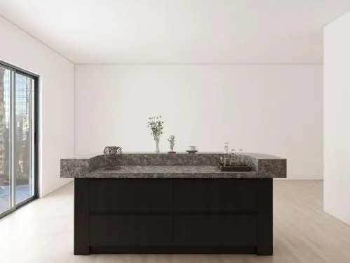 Dark island with a thick gray stone top in a bright room with sliding glass doors
