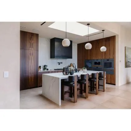 Side view of a white island with walnut stools, a black box hood and built-in ovens