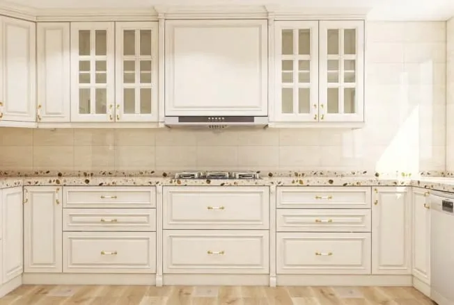 Cream raised-panel cabinets with mullioned glass uppers, brass knobs and a slim hood over the cooktop