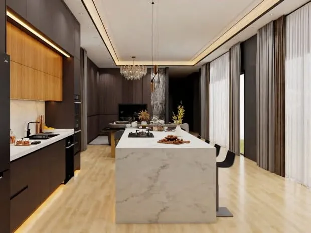 Charcoal kitchen with walnut-tone upper cabinets, a white marble waterfall island and a crystal chandelier beyond
