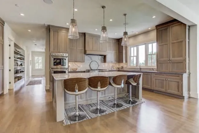 Gray-washed oak kitchen with an island seating four under three glass bell pendants