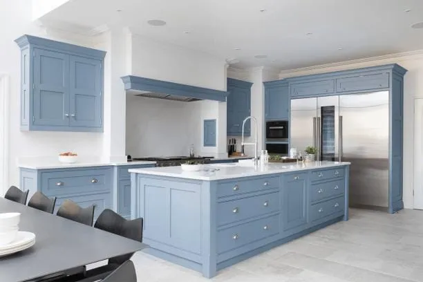 Blue inset Shaker kitchen with a large island, white quartz counters and a stainless refrigerator