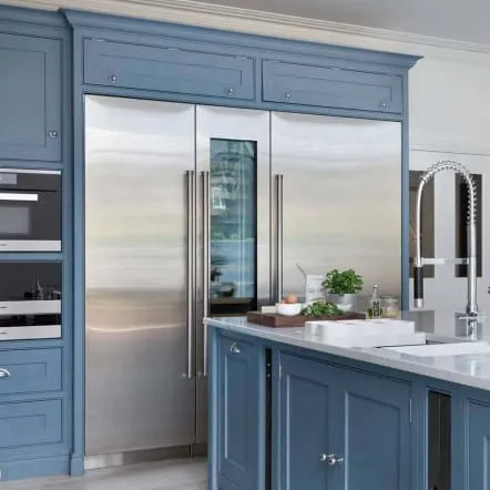 Stainless French-door refrigerator set into blue cabinetry with crown molding