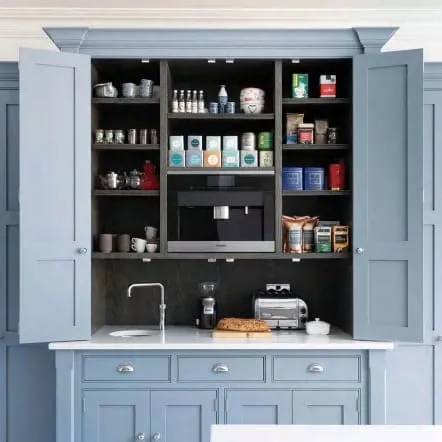 Blue breakfast cupboard with open bifold doors showing a built-in coffee machine, shelves, a small sink and a toaster