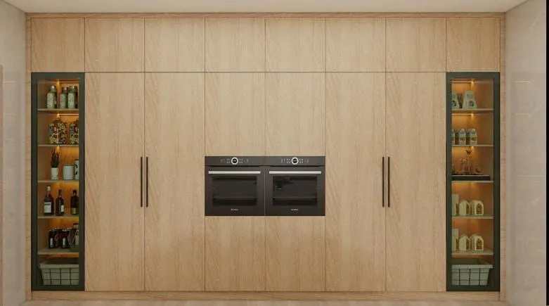 Full-height light oak cabinet wall with two built-in ovens and lit glass display columns on each side
