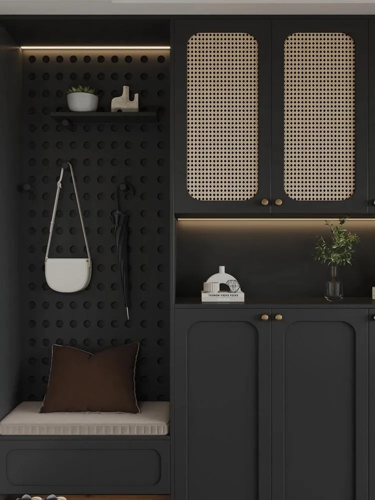Close view of a black pegboard with hooks, a cushioned bench and cane-panel cabinet doors