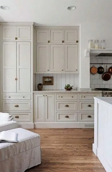 Greige cabinet wall with drawers and a hanging pot rail beside a wood floor
