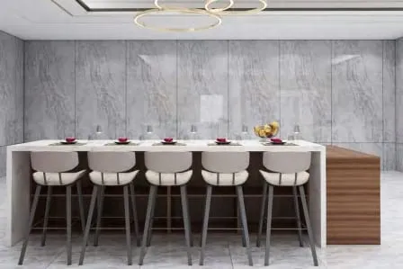 Island seating five upholstered stools against gray marble wall panels under a gold ring chandelier