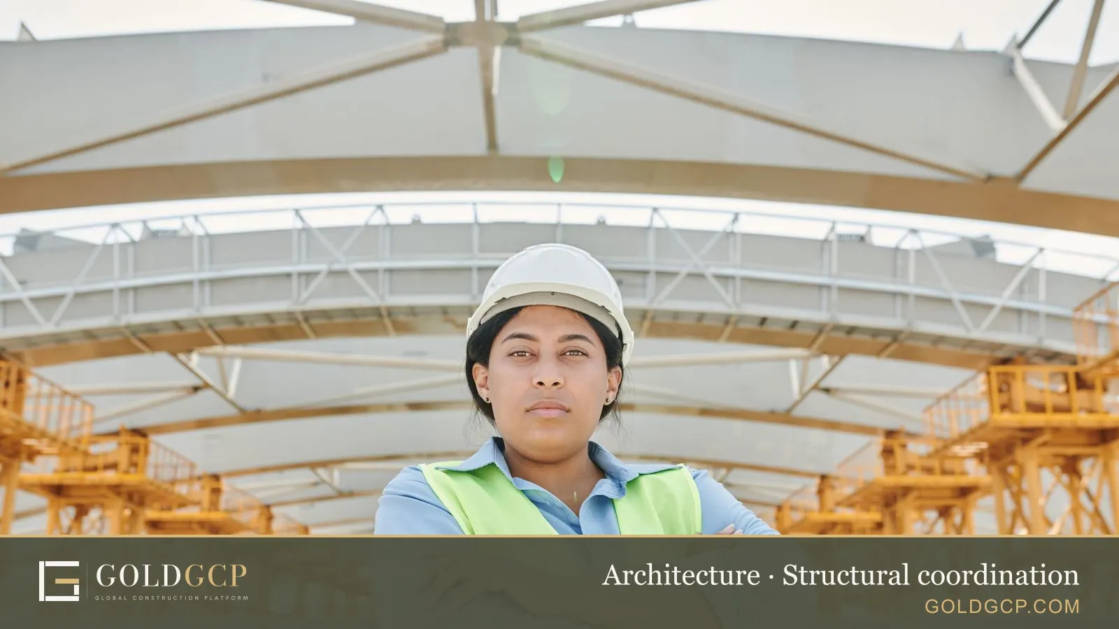 An engineer in safety gear at a site with a steel frame behind her