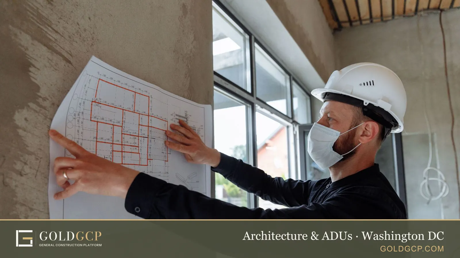 Architect in hard hat and mask reviews floor plans on site for a new construction project.