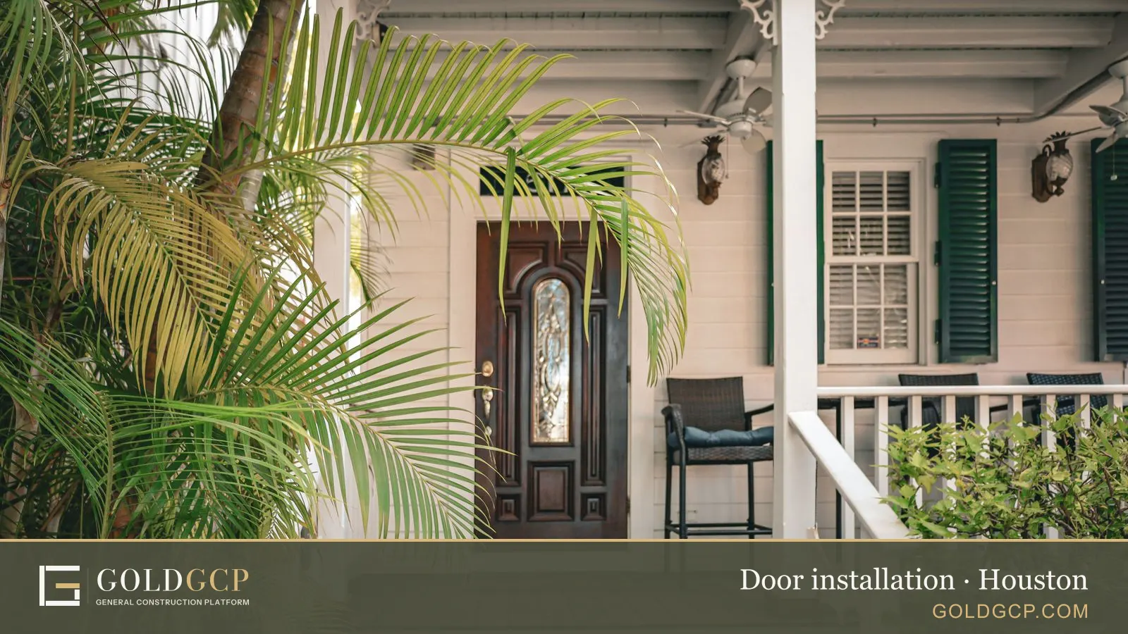 A wood front door with an oval glass insert on a covered porch framed by palm fronds