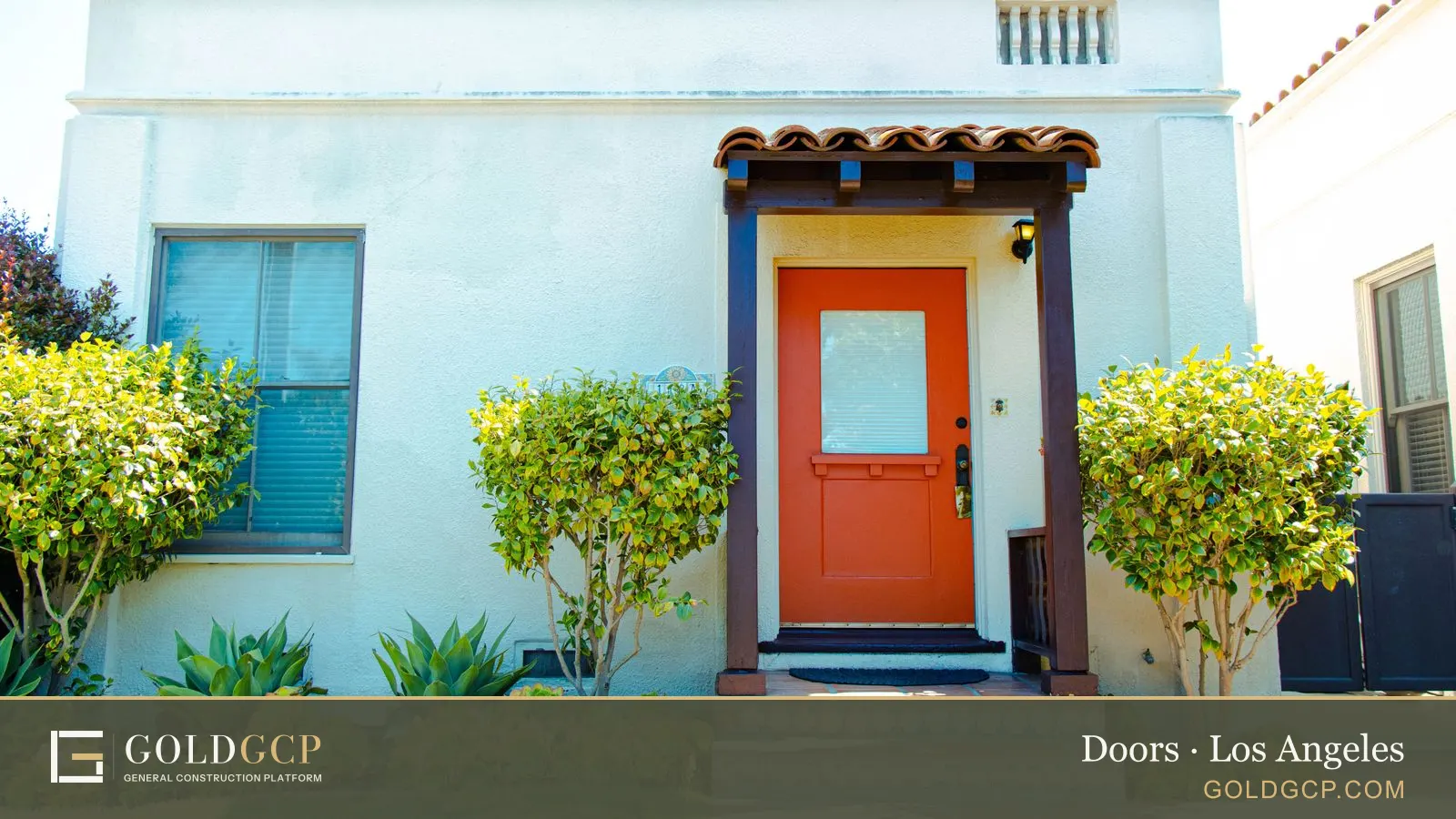 A stucco Spanish style home with an orange front door under a small tiled awning