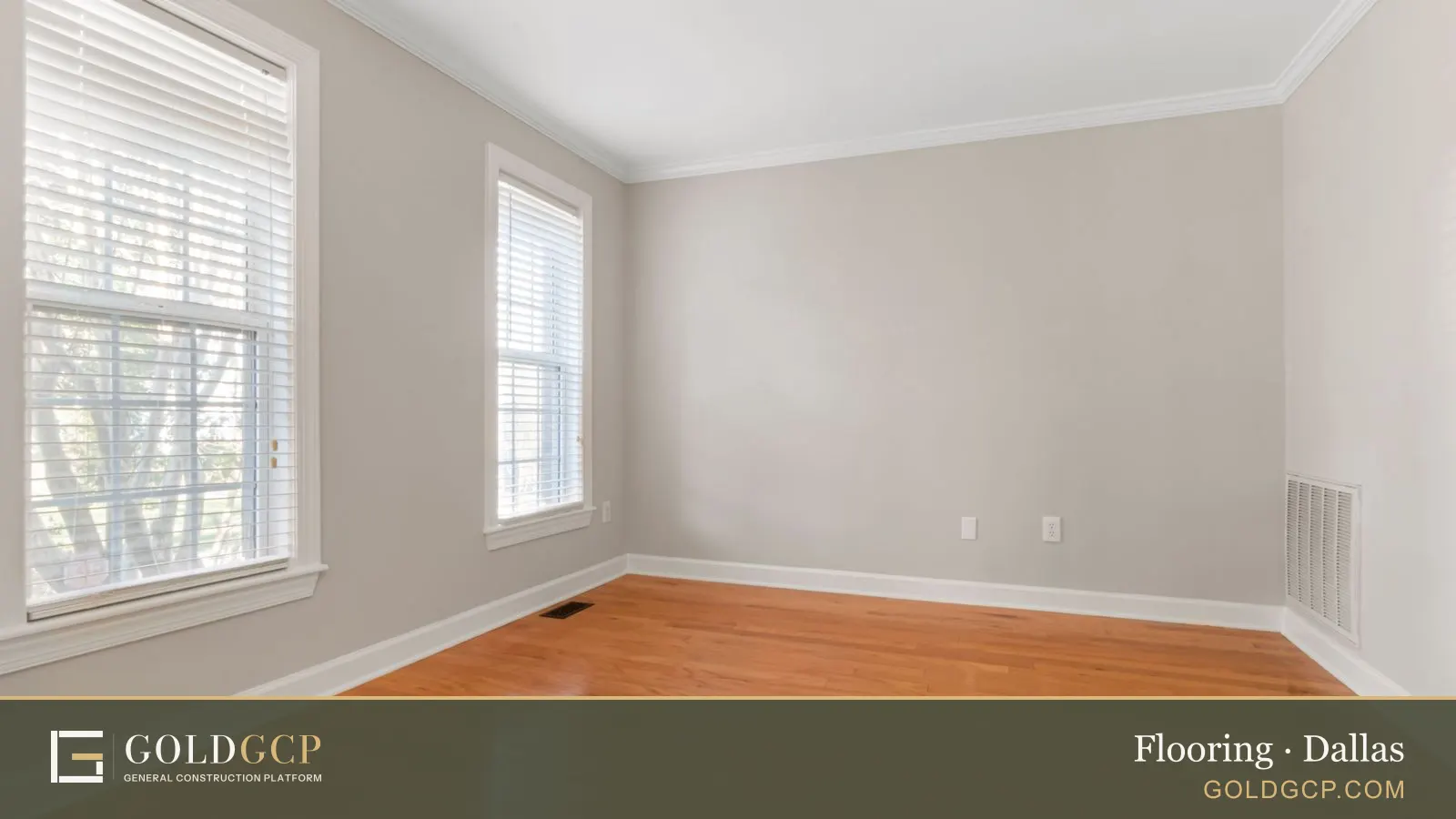 An empty room with honey-toned hardwood floors, white trim and two windows