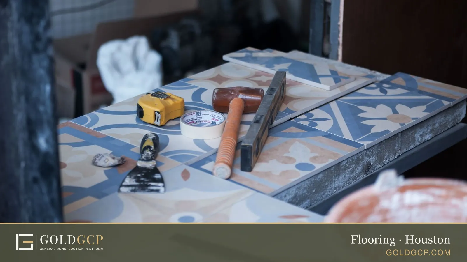 Patterned cement tiles, a mallet, a tape measure and a trowel laid out for tiling work