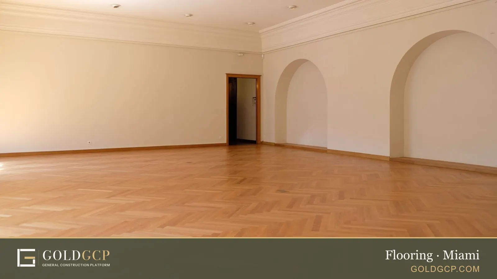 Large empty room with elegant wooden flooring, arches, and natural lighting.