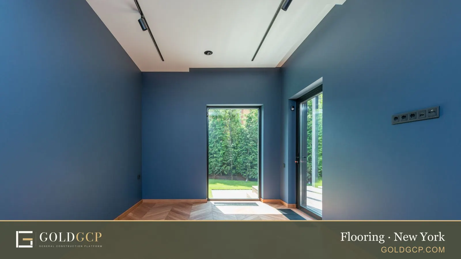 A room with a wooden herringbone floor and glass doors to a garden