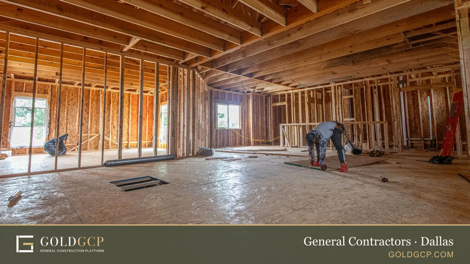 A wood-framed house under construction in the Dallas area, with a worker on the subfloor