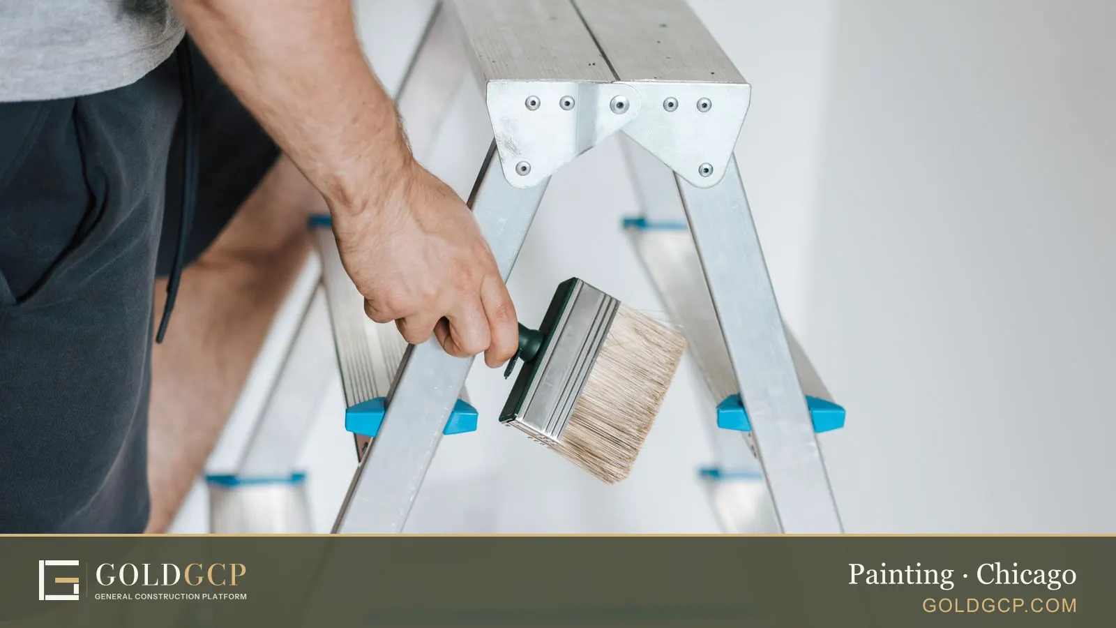 Side view of a man standing on a ladder with a tool, painting a wall in a flat.