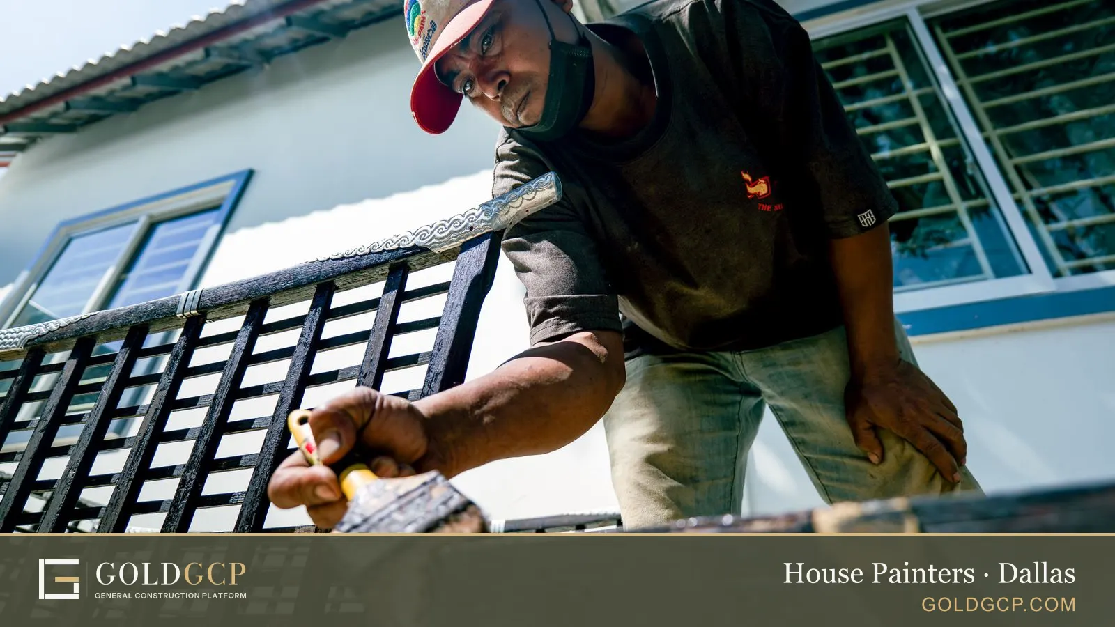 A painter brushing new paint onto a metal railing outside a house
