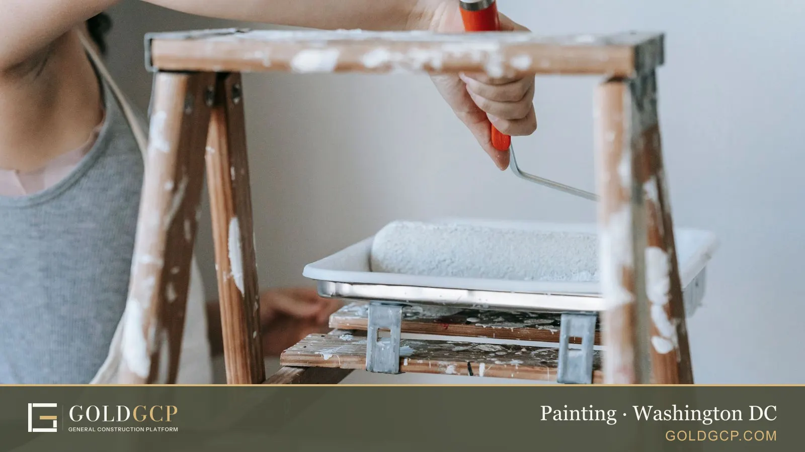 Adult woman using a roller and ladder to paint a room wall indoors.