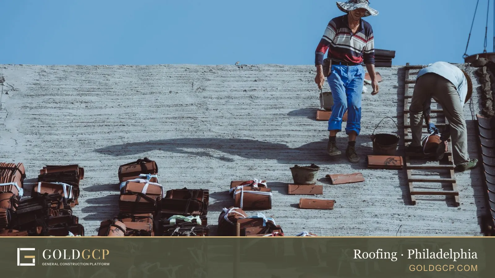 Two construction workers installing roof tiles on a building under a clear blue sky.