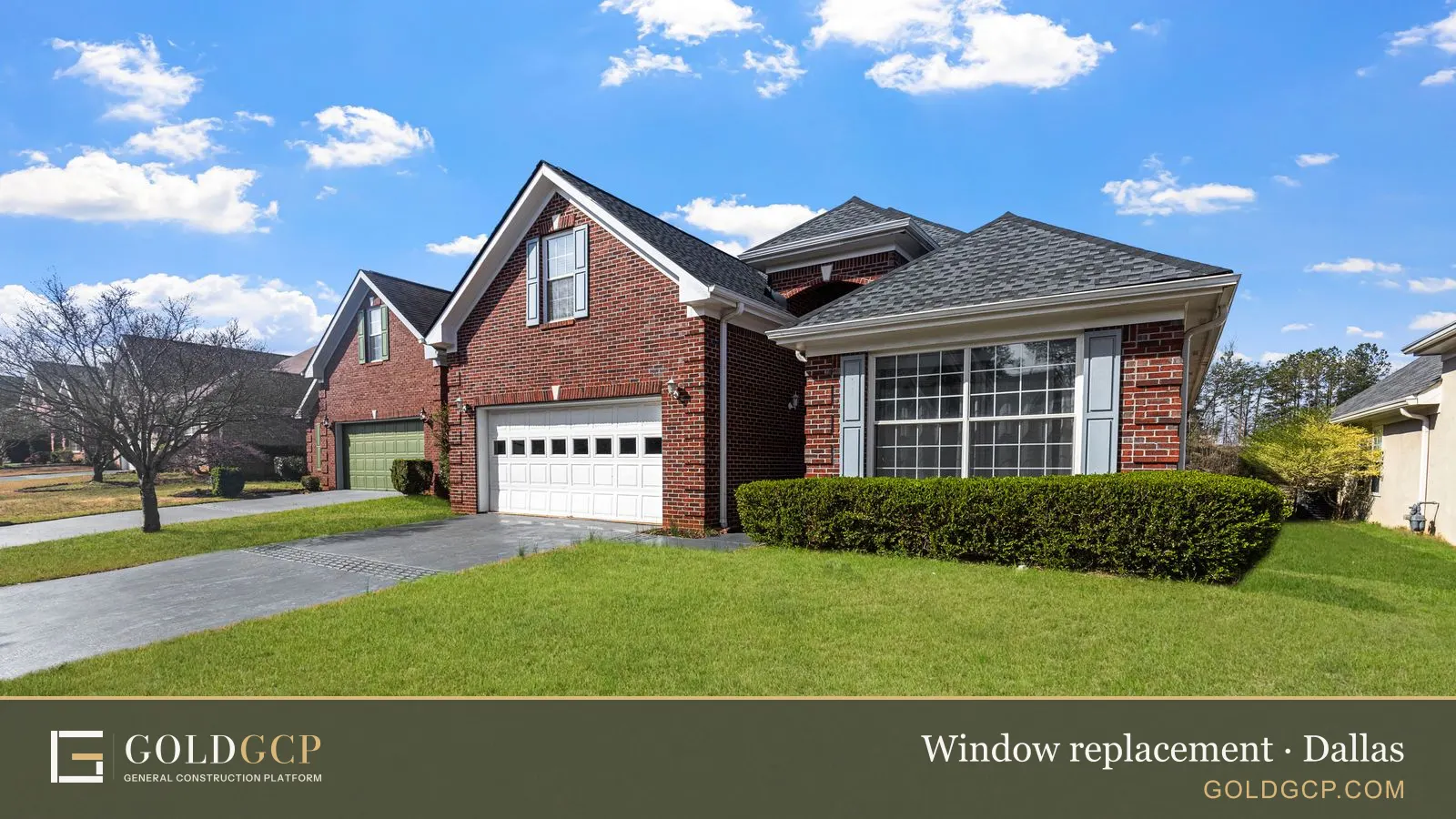 A red brick suburban house with a large front window, a two-car garage and a green lawn